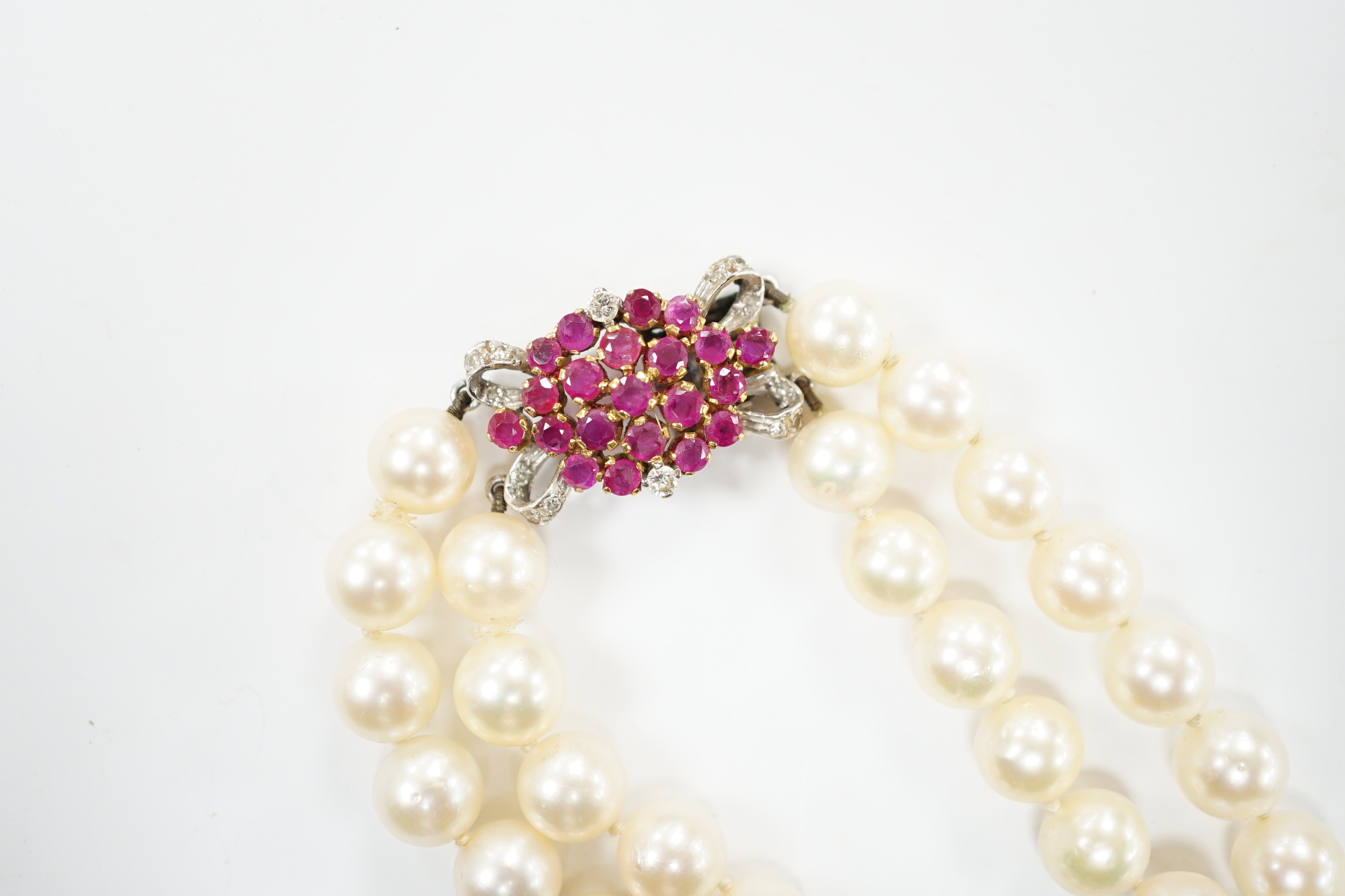 A double strand cultured pearl choker necklace with yellow and white metal, ruby and diamond cluster set clasp, 40cm.